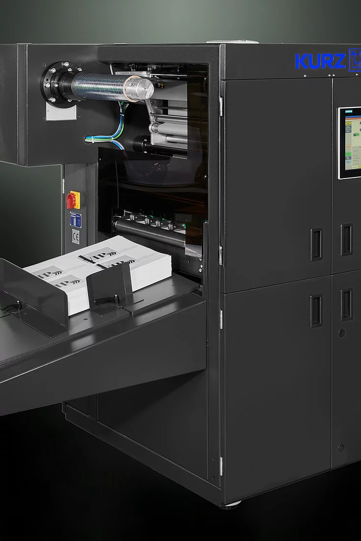 Digital Embellishment Solution from KURZ with open compartment, processing stacked printed sheets labeled "VIP".