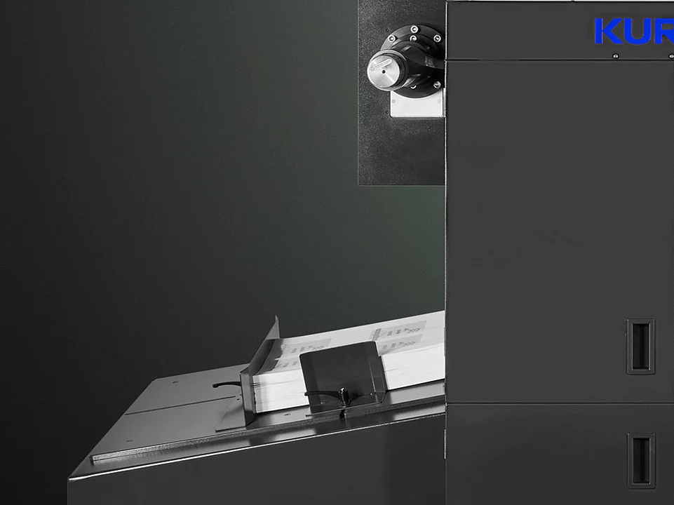 Digital Embellishment Solution from KURZ with open compartment, processing stacked printed sheets labeled "VIP".