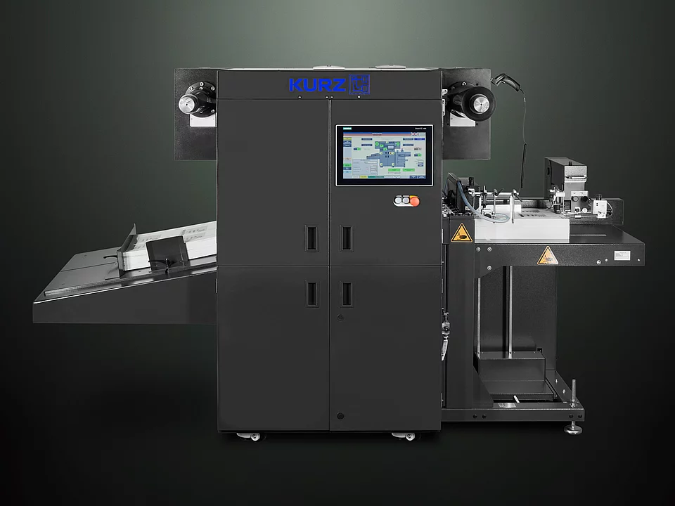 Digital Embellishment Solution from KURZ with open compartment, processing stacked printed sheets labeled "VIP".