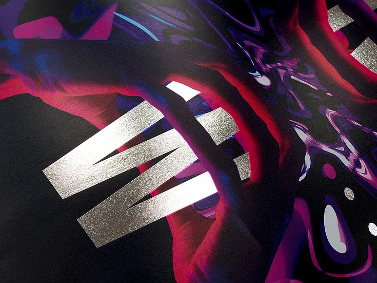 Close-up of a dark, glossy surface with bold silver letters spelling ‘WIN’ and abstract colorful patterns in red and purple.