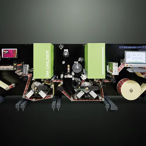 Digital Embellishment Solution with green panels, multiple rollers, two screens, and roll-fed colorful label material.