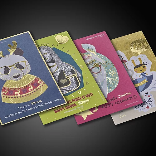 Vier farbenfrohe Grußkarten mit Goldfolienverzierungen, darauf abgebildet sind ein Panda in festlicher Kleidung, eine Löwenkönigin, ein Kaninchen mit Brille und ein Piratenhasen, jeweils mit verspielten Designs und personalisierten Namen.