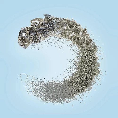 Abstrakte silberne Spiralform aus Folie, Drähten und Partikeln auf hellblauem Hintergrund.