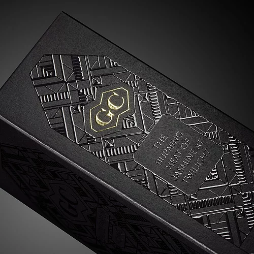 Luxuriöse schwarze Verpackung mit aufwendigen geometrischen Prägungen, goldenem „GC“-Logo und silbernem Prägedruck mit den Worten „The burning heat of jasmine at twilight“ (Die brennende Hitze des Jasmins in der Dämmerung) und „Made in France“ (Hergestellt in Frankreich).