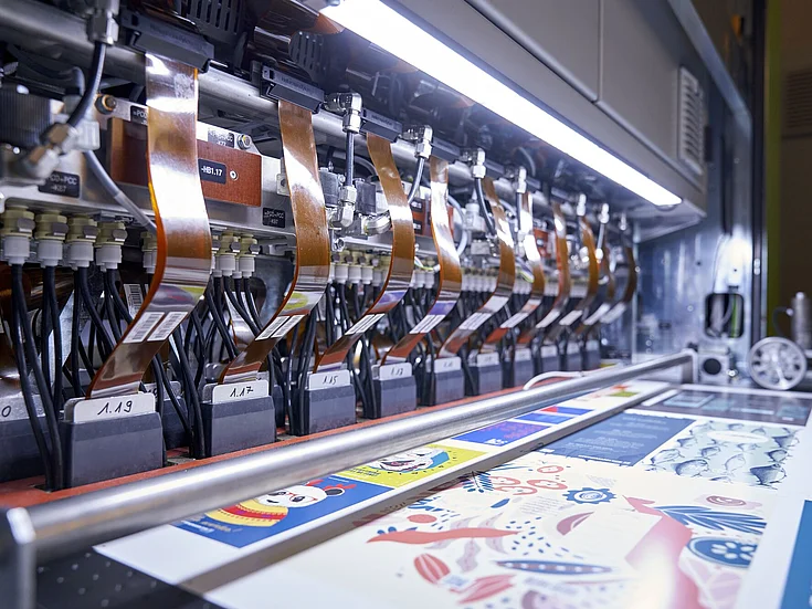 Digital printing machine producing colorful sheets with copper cables.