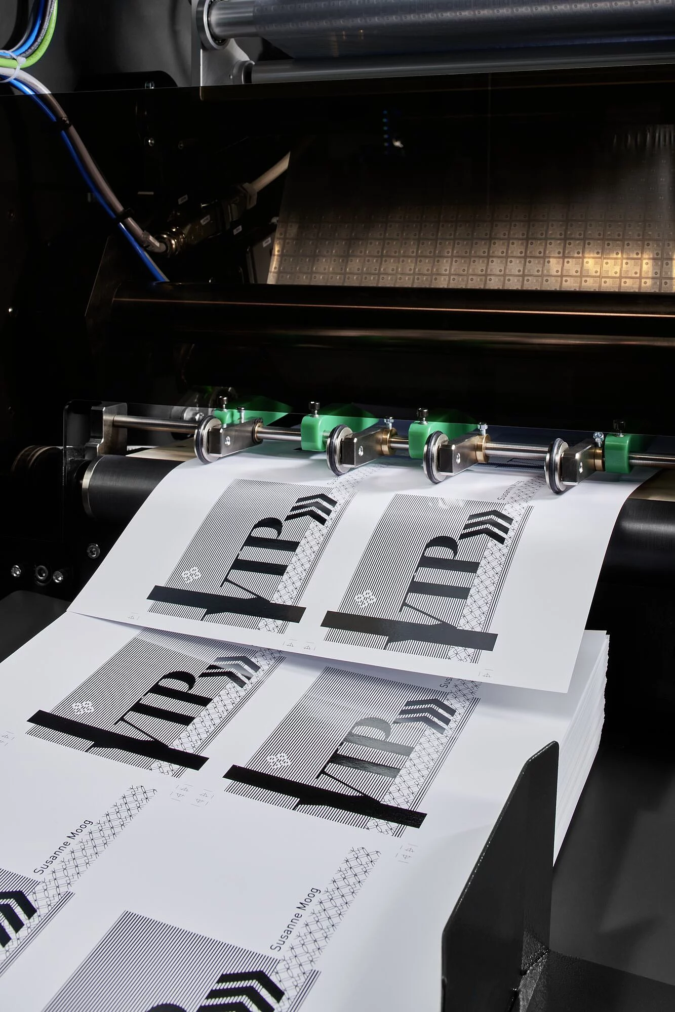 Close-up of a printing machine producing sheets with a design labeled ‘LUXORO’ featuring intricate line patterns and holographic elements.