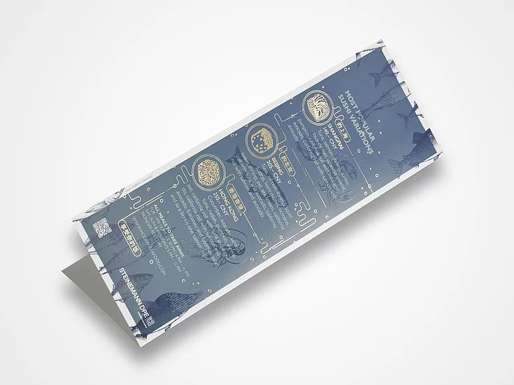 Folded sushi-themed print sample with gold foil accents, featuring illustrated ingredients and location-specific sushi variations, produced by STEINEMANN DPE.