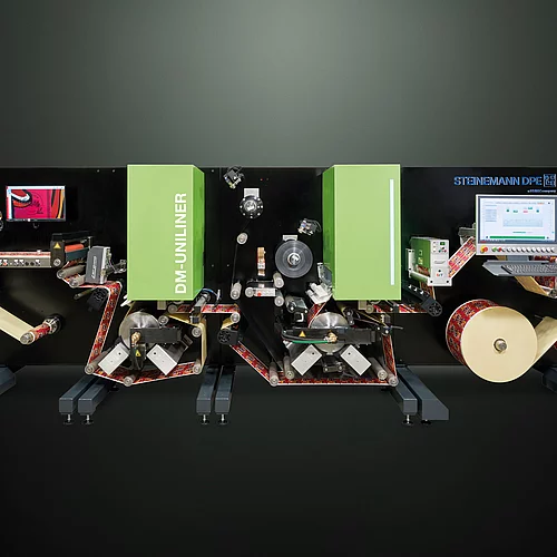 Digital Embellishment Solution with green panels, multiple rollers, two screens, and roll-fed colorful label material.