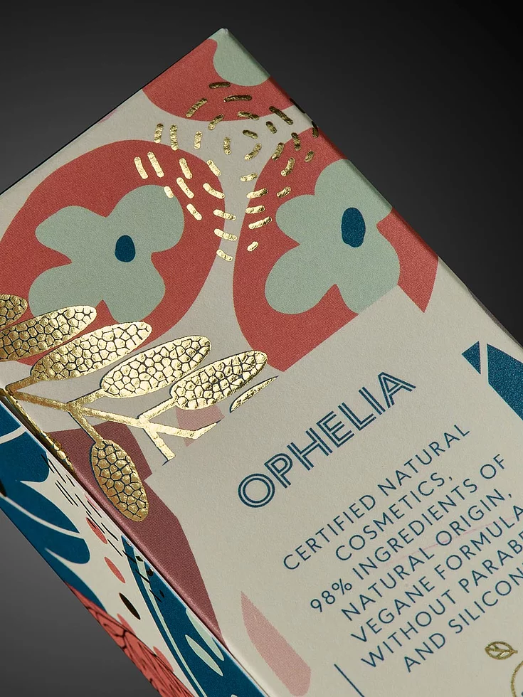 Close-up of OPHELIA cosmetic packaging with colorful floral design and gold foil embellishment