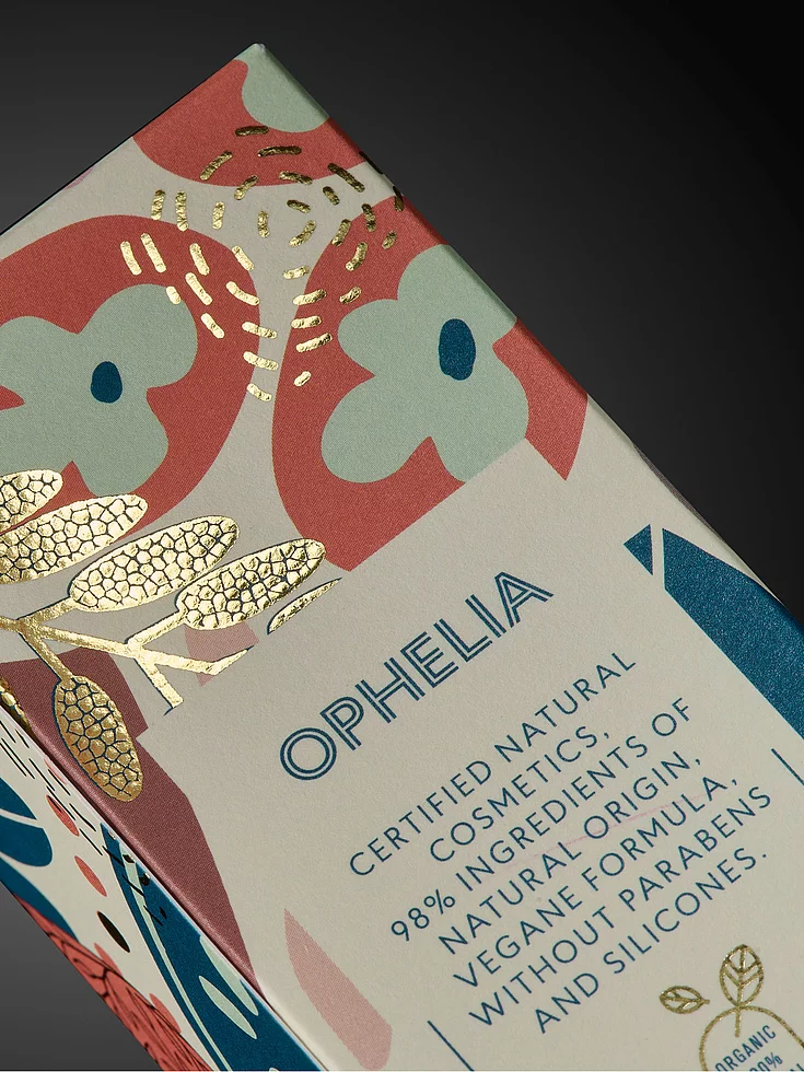 Close-up of OPHELIA cosmetic packaging with colorful floral design and gold foil embellishment.