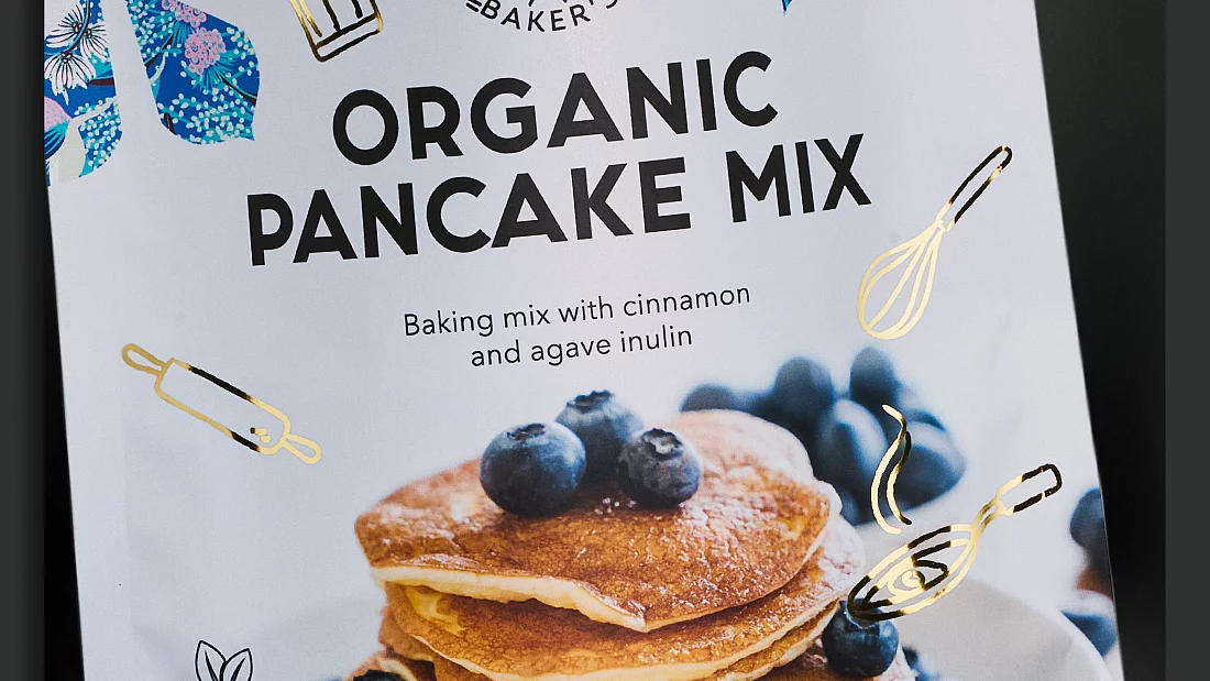 Organic pancake mix package with blueberries, gold foil baking icons, vegan and gluten-free labels, and KURZ logo.