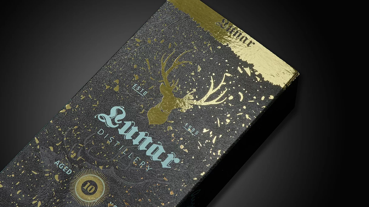 Black and gold packaging box with a gold foil deer head and decorative splashes, labeled "Lunnar Distillery" aged 10 years.