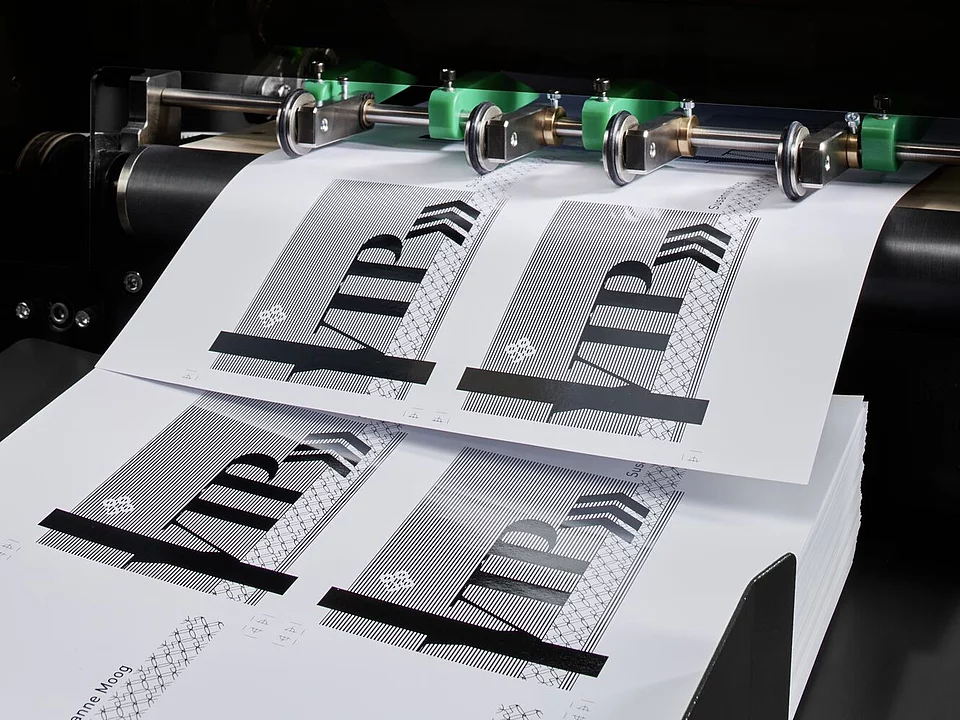 Digital Embellishment Solution from KURZ with open compartment, processing stacked printed sheets labeled "VIP".