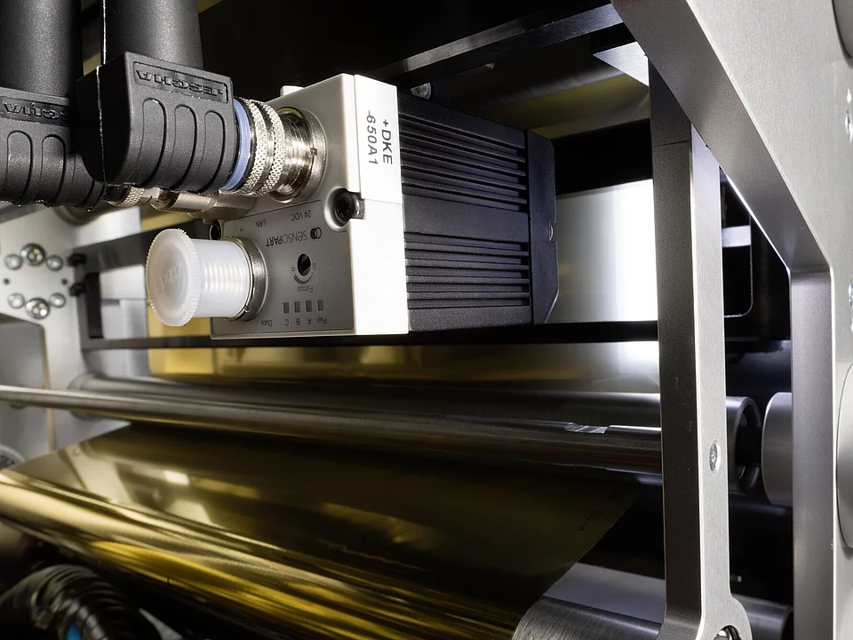 Close-up of industrial sensor and roller mechanism inside a machine.