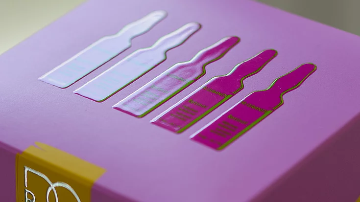 Close-up of a purple product box featuring a raised, glossy design of five ampoules