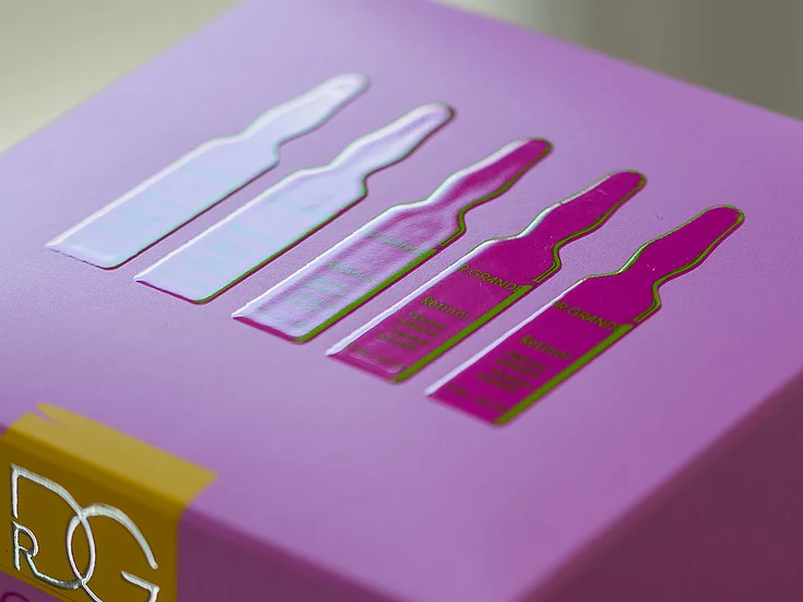Close-up of a purple product box featuring a raised, glossy design of five ampoules