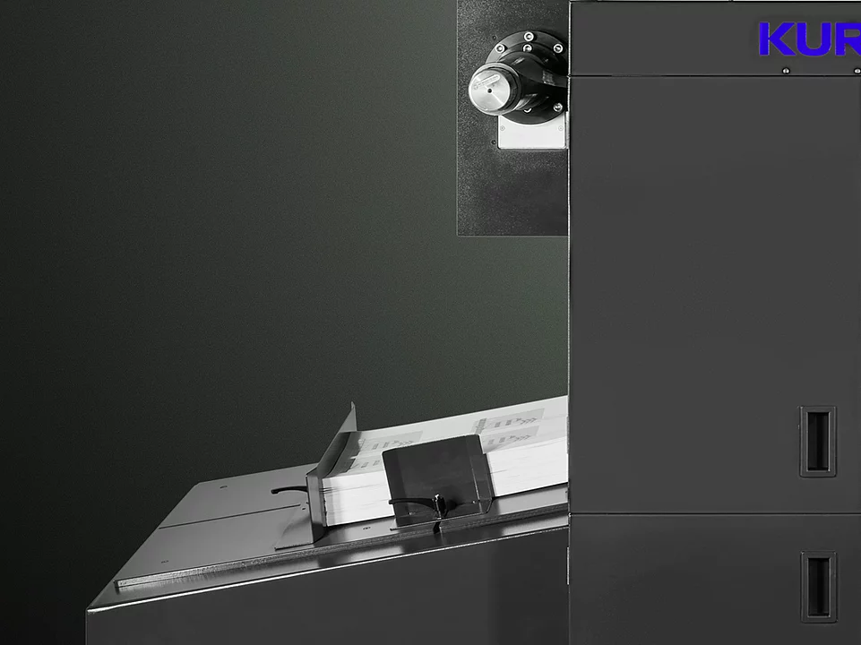 Digital Embellishment Solution from KURZ with open compartment, processing stacked printed sheets labeled "VIP".
