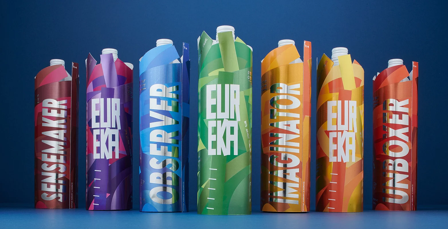 Drink packaging in various vibrant colors, standing in a row on a blue background, showcasing bold "EUREKA" text and modern graphic designs.