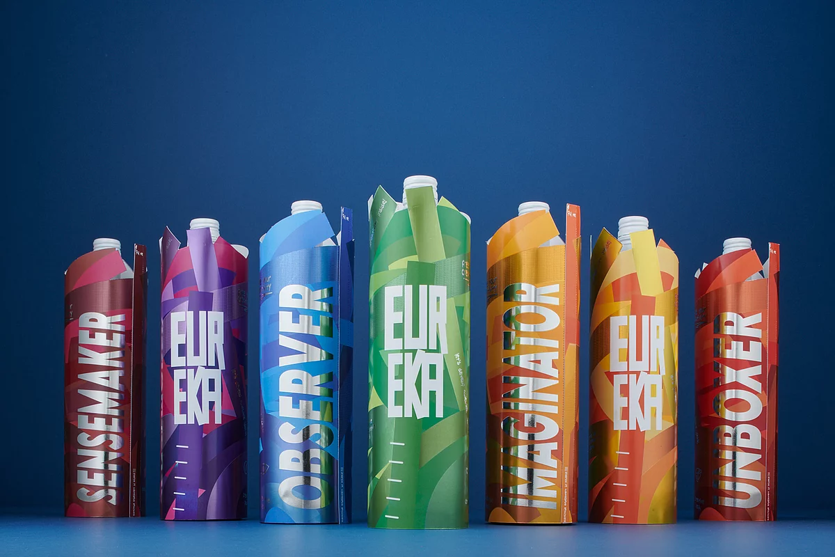 Drink packaging in various vibrant colors, standing in a row on a blue background, showcasing bold "EUREKA" text and modern graphic designs.