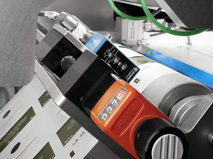 Close-up of precision components and sensors in a KURZ digital embellishment machine processing printed labels.