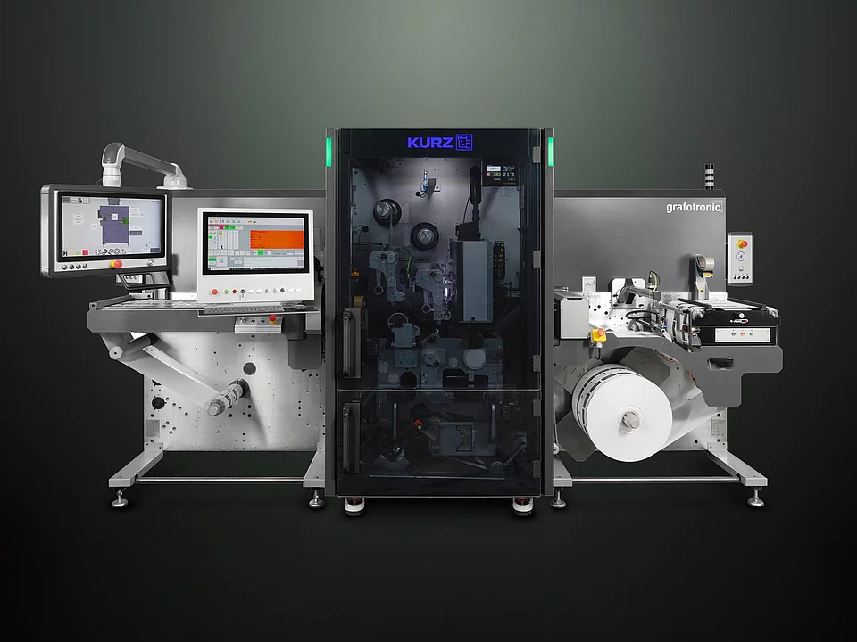 Digital embellishment machine with control screens, labeled "KURZ" and "grafotronic," showing a roll of material. 