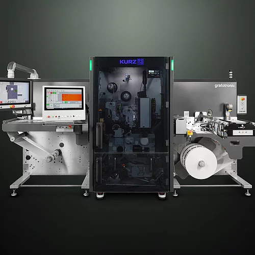 Digital embellishment machine with control screens, labeled "KURZ" and "grafotronic," showing a roll of material. 