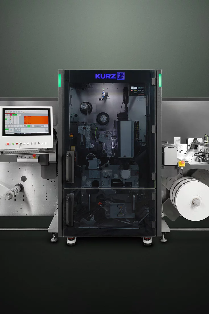 digital embellishment machine with control screens, labeled "KURZ" and "grafotronic," showing a roll of material. 