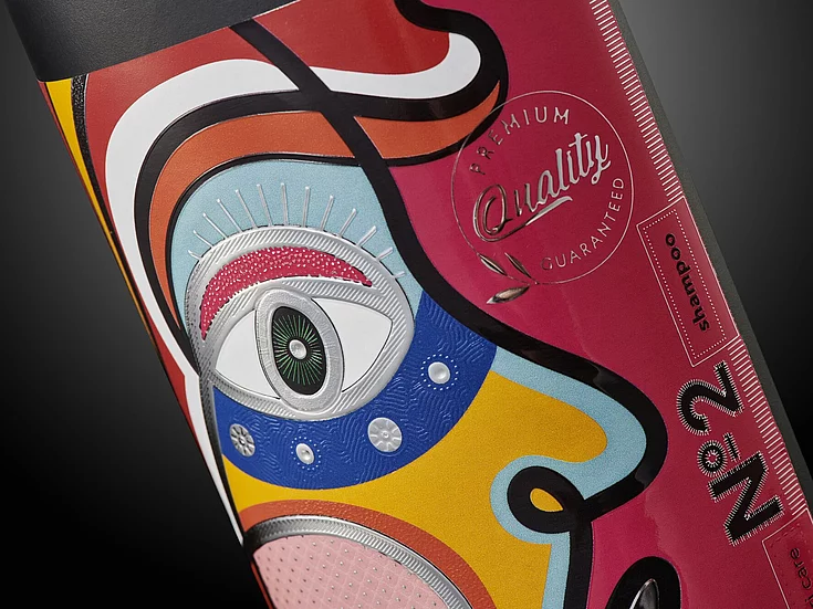 Close-up of vibrant shampoo packaging with abstract face illustration, featuring silver foil, tactile embossing, and premium quality label design.
