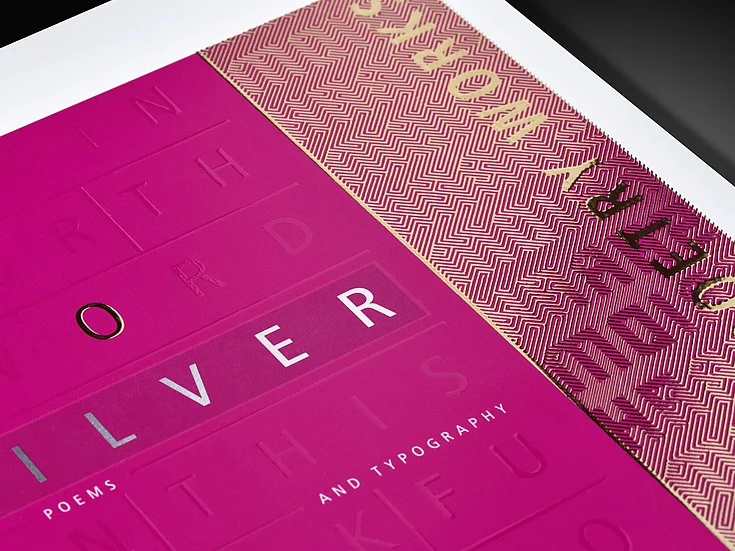 Close-up of a pink printed sheet with silver and gold foil accents, embossed typography, and geometric pattern, showcasing high-end print finishing for poetry and design.
