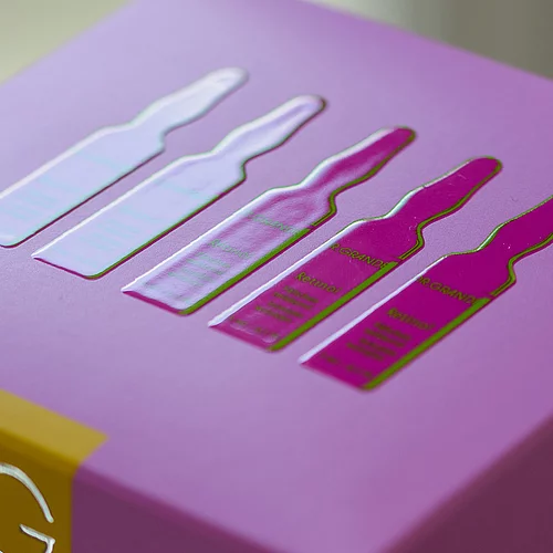 "Nahaufnahme einer lilafarbenen Produktverpackung mit glänzend erhabener Darstellung von fünf Ampullen "