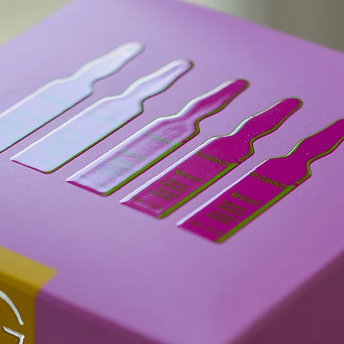 Close-up of a purple product box with glossy raised design of five ampoules.