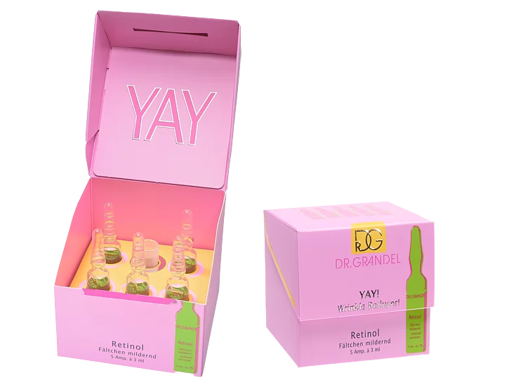 Offene rosa Schachtel mit sechs Glasampullen des Produkts Dr. Grandel Retinol im Inneren, auf dem Innendeckel ist „YAY“ aufgedruckt.