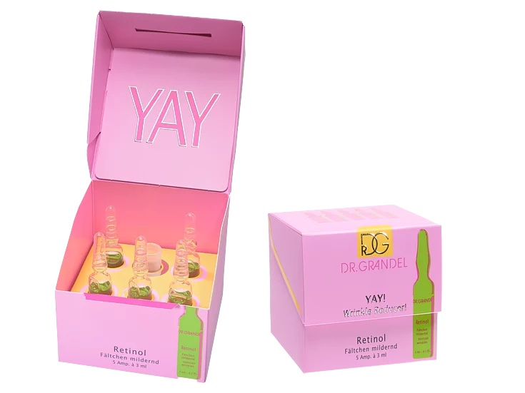 Open pink box with six glass ampoules of Dr. Grandel Retinol product inside, with ‘YAY’ printed on the inner lid.