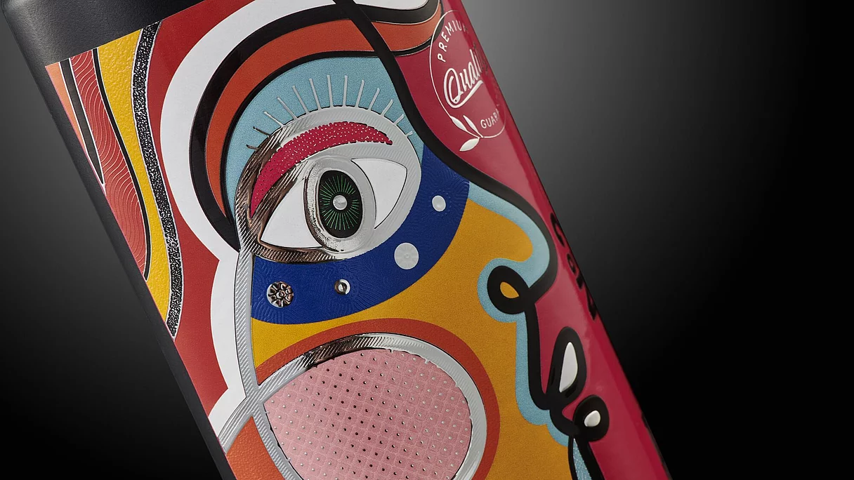 Close-up of a colorful, abstract face design with embossed and metallic details on a product label.