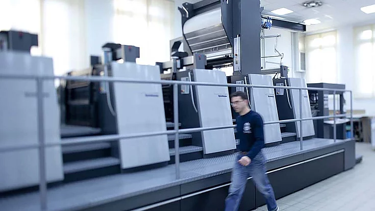 person is walking in front of printing machines